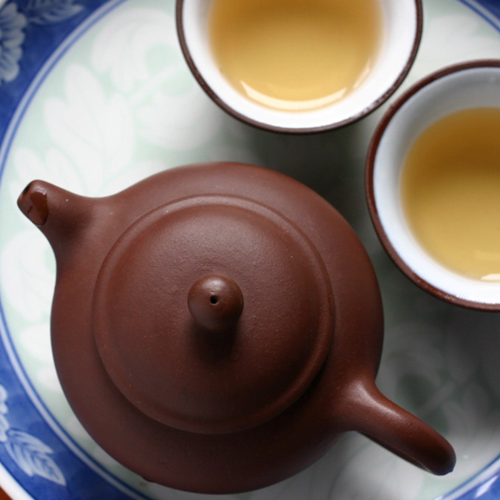 A traditional teapot and cups set with Oolong tea, reflecting the rich and complex flavors of this semi-oxidized type of tea.