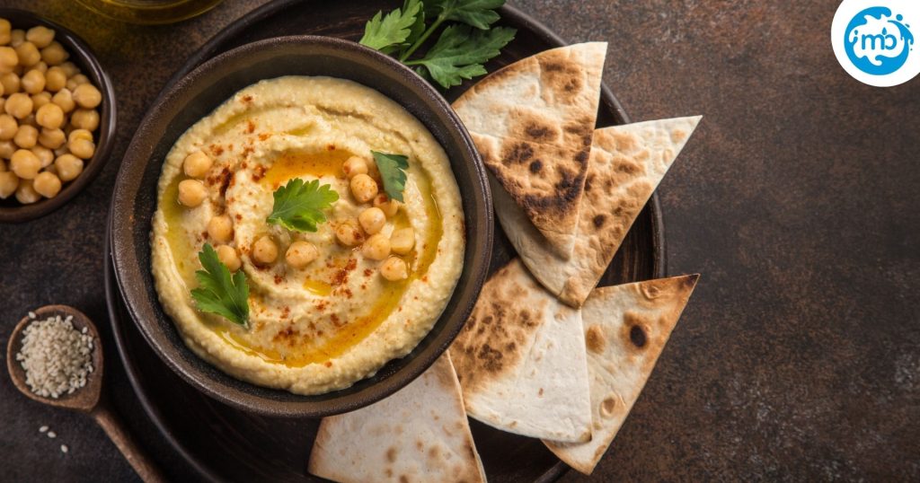 hummus dip and olive oil, with pita bread served in a wooden plate
