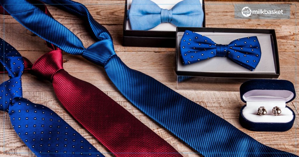 Red and blue silk ties with blue bows and cufflinks kept on a wooden table for father's day gift ideas