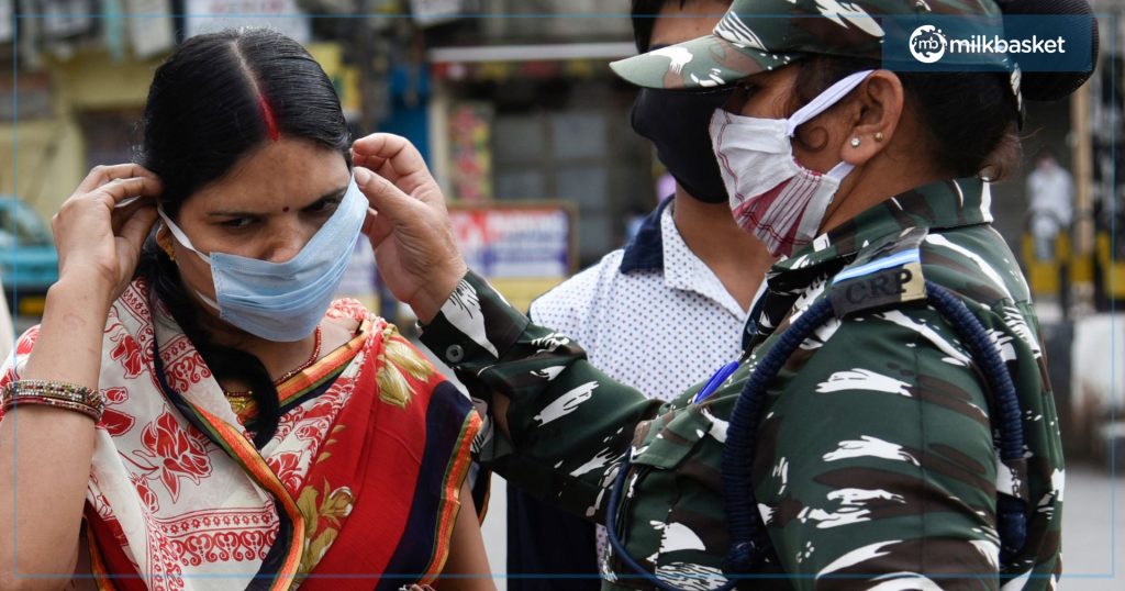  a paramilitary woman officer on duty helping a civilian woman in tying a face mask properly during lockdown, kindness