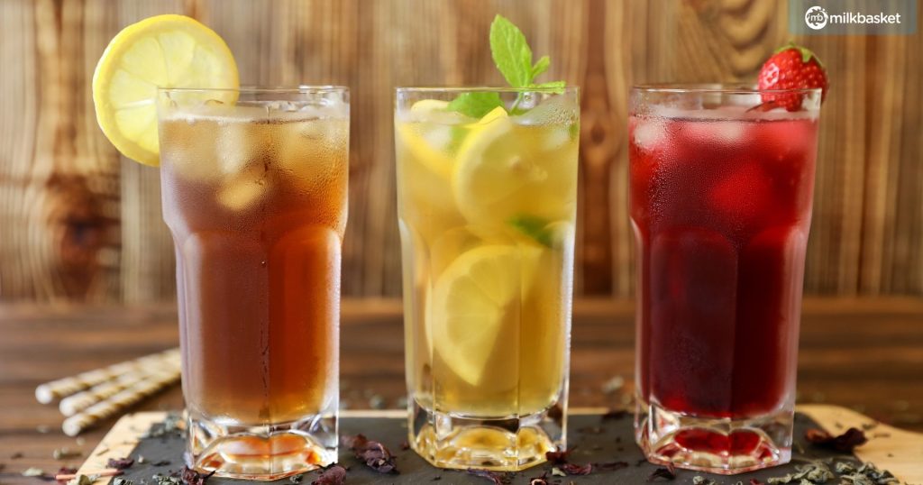 Three glasses of different iced tea, black, green with lemon and mint, hibiscus tea on the wooden background, Close-up