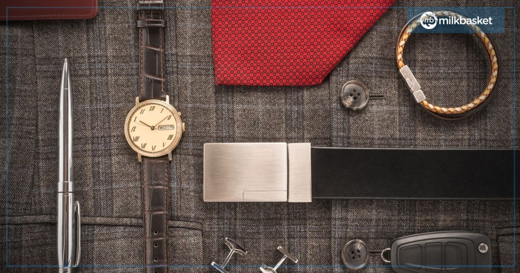 A watch, black belt, pen, red tie and a bracelet kept on a fabric background