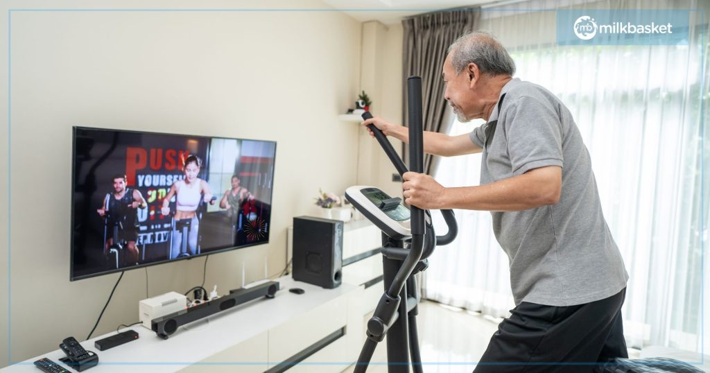 An aged Indian man working out on an elliptical exercise machine, online fitness class