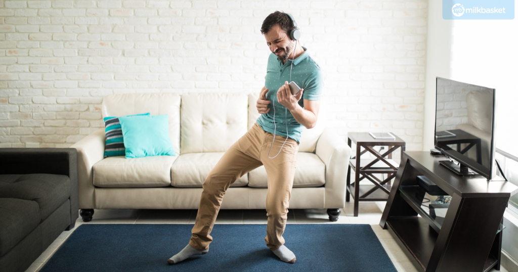 man dancing alone at home, headphones on, semi-casual attire.