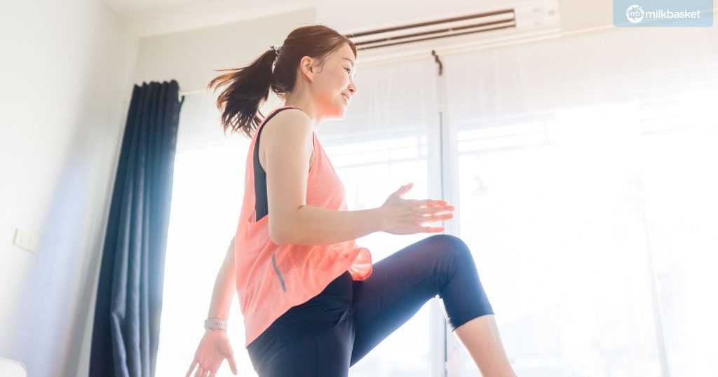woman taking an online dance class at home, in workout clothes, smiling.
