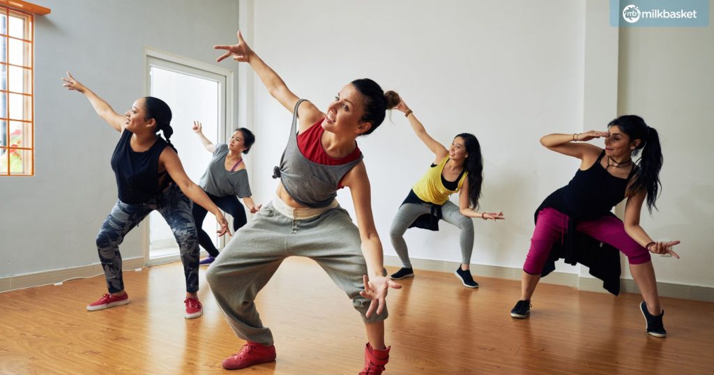 a group of female dancers in workout clothes, in a dance class for women, performing aesthetic dance fitness movements