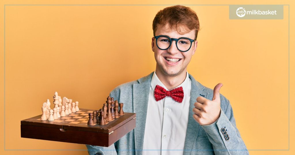 A boy with glasses and a set of chess in the hand, showing thumbs up 