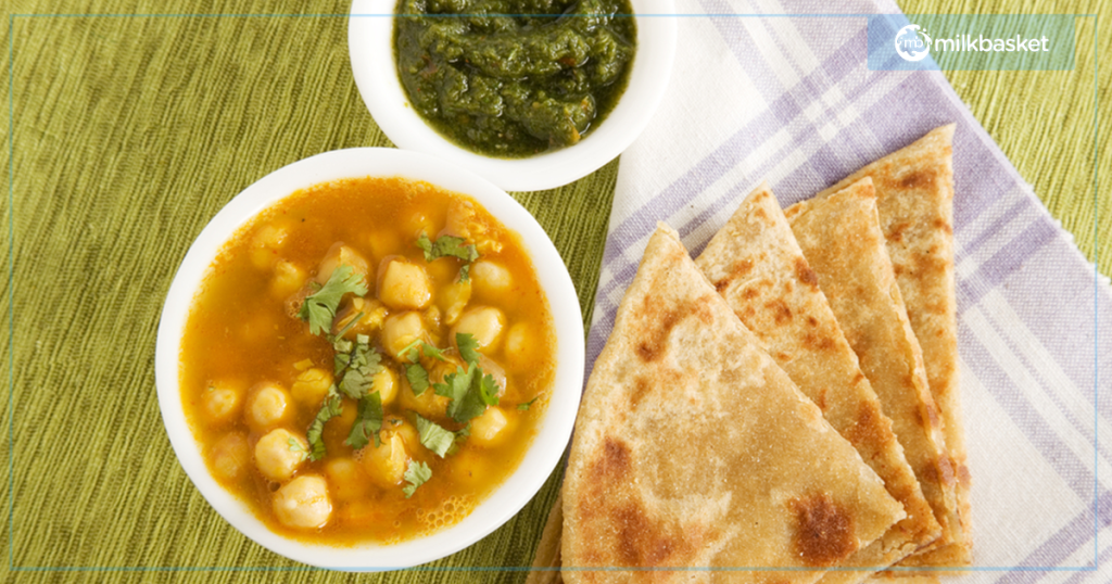 Normal daily lunch meal with green chutney, parathas, and chhole sabzi