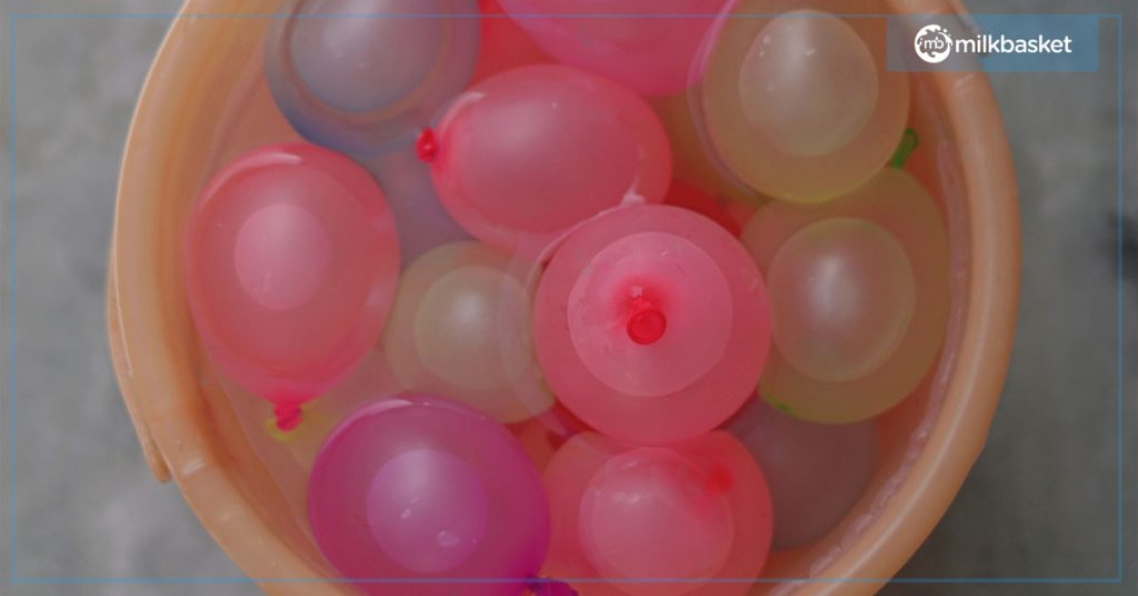 bucket filled with water with holi balloons