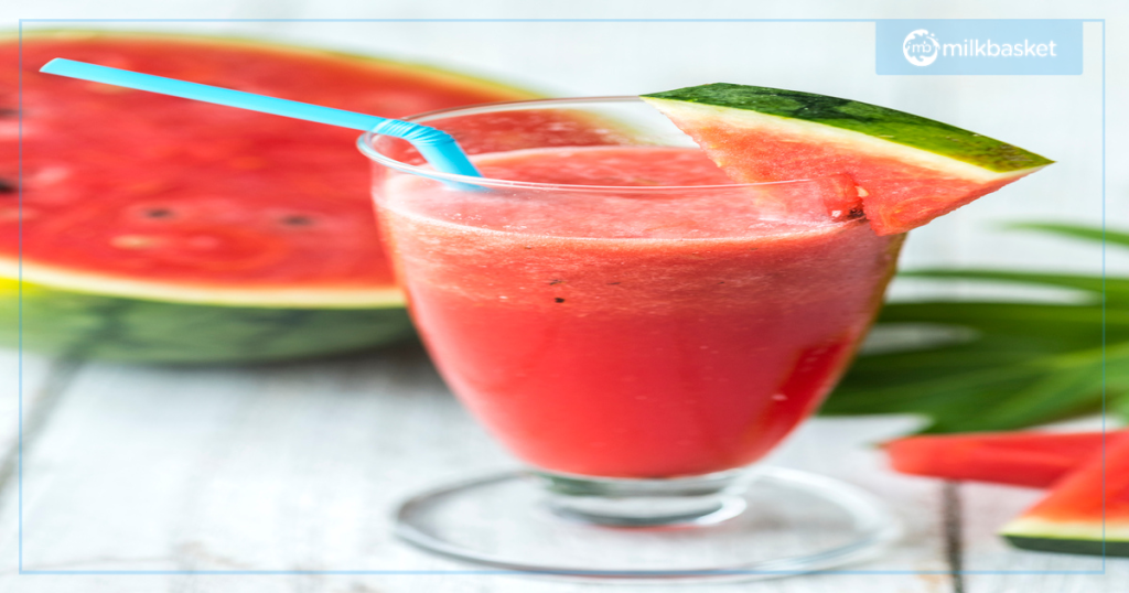 Watermelon smoothie with a straw and a slice of watermelon on the side.