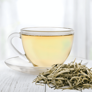 A clear cup of pale yellow white tea with loose leaves beside it, emphasizing the light and subtle flavor of this delicate type of tea.