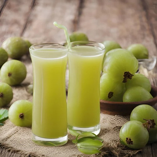 Two glasses filled with light green amla juice, surrounded by fresh amla fruits.