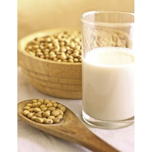 A glass of soy milk with a wooden spoon and bowl of soybeans, highlighting soy as a key protein pick for vegetarians