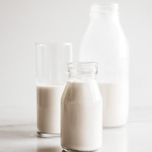 Bottles and glasses of fresh milk, a vital dairy product used in various fasting recipes during Janmashtami 2024.