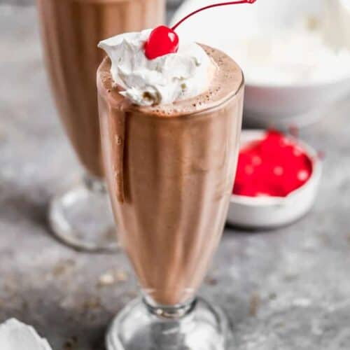 A classic chocolate milkshake recipe topped with whipped cream and a cherry, perfect for a sweet and creamy treat.