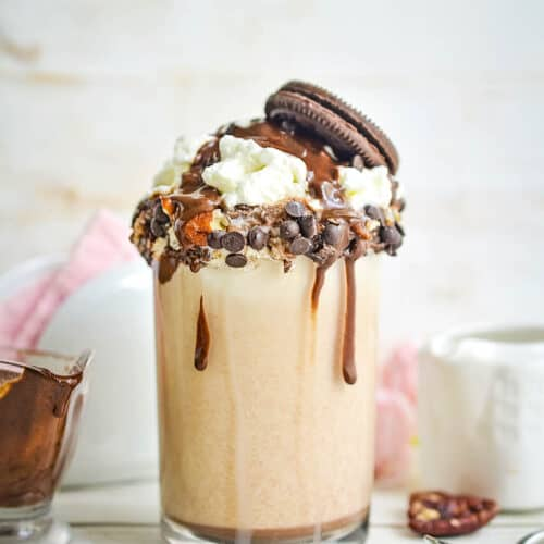 A decadent Cookie Dough chocolate milkshake recipe, loaded with whipped cream, chocolate chips, and topped with an Oreo cookie.